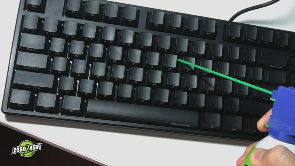 blowing compressed air between key caps on keyboard