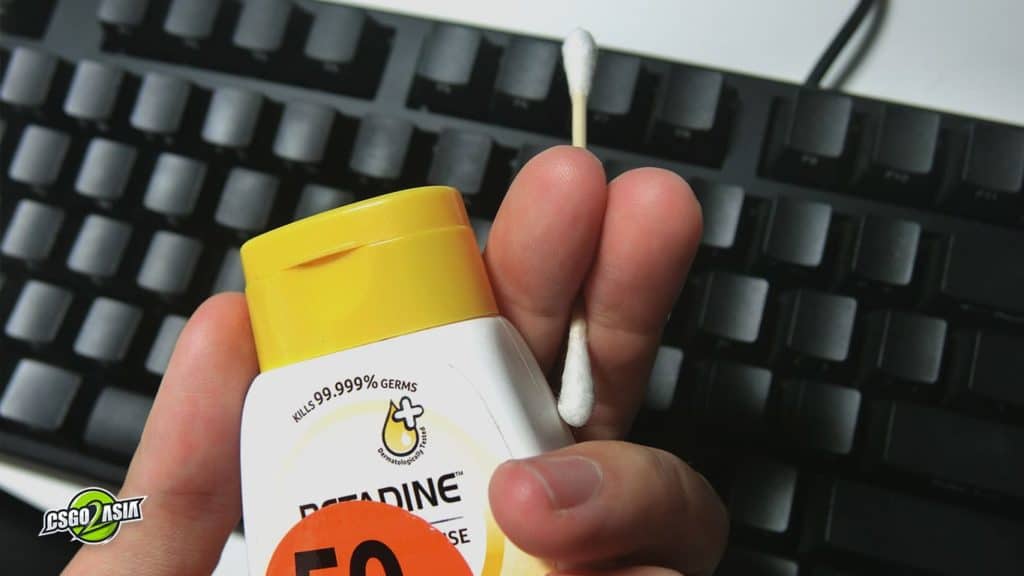 using cotton bud and hand sanitizer to clean keyboard